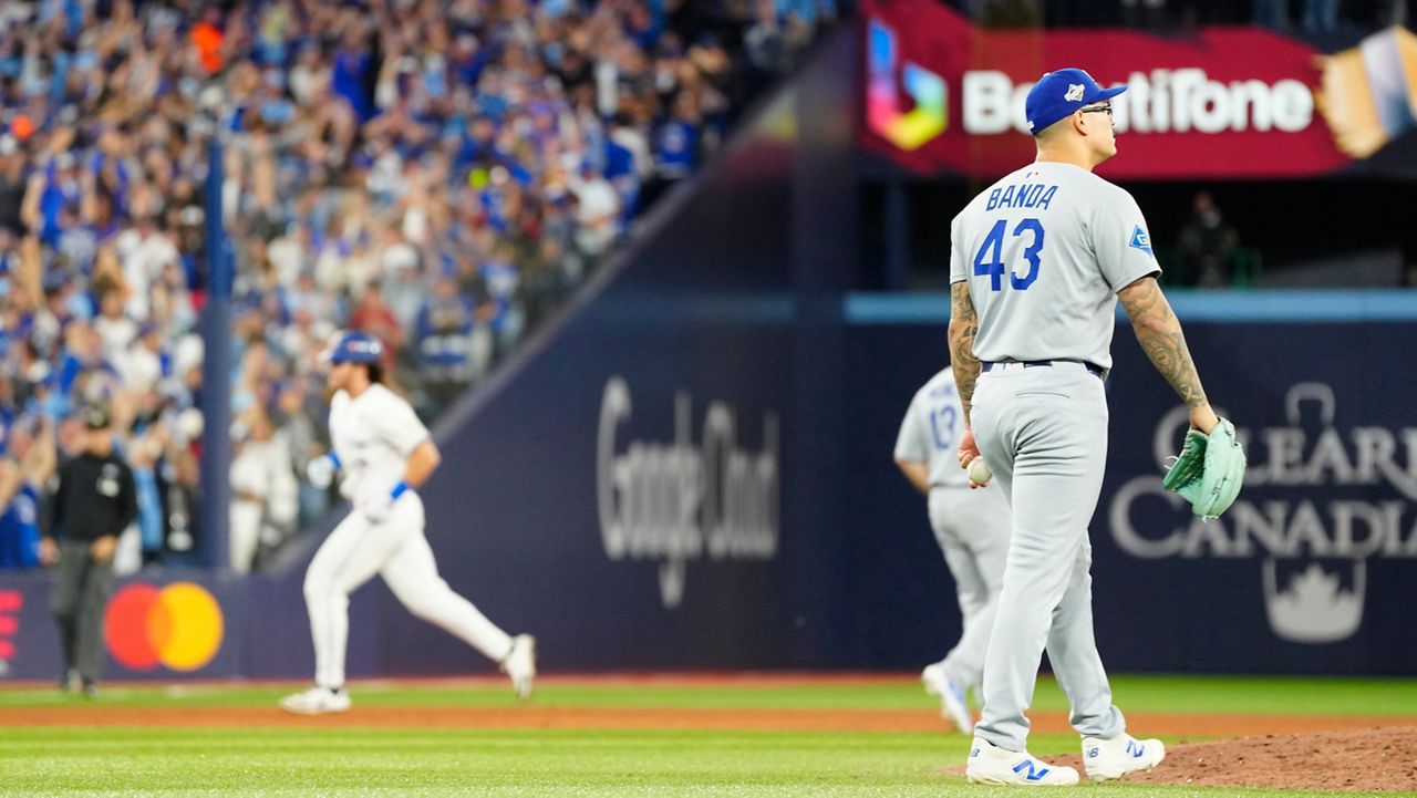 Los Angeles Dodgers pitcher Anthony Banda (43) reacts as Toronto Blue Jays' Addison Barger, back left, rounds the bases after hitting a grand slam during the sixth inning of Game 1 of baseball's World Series in Toronto, Friday, Oct. 24, 2025. (Frank Gunn/The Canadian Press via AP)