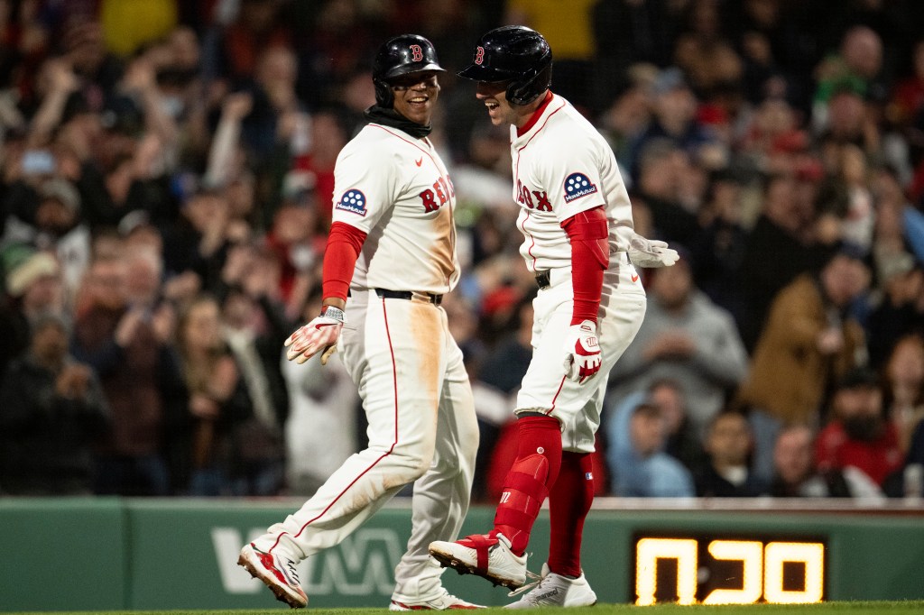 Two baseball players in Boston Red Sox uniforms celebrating on the field.