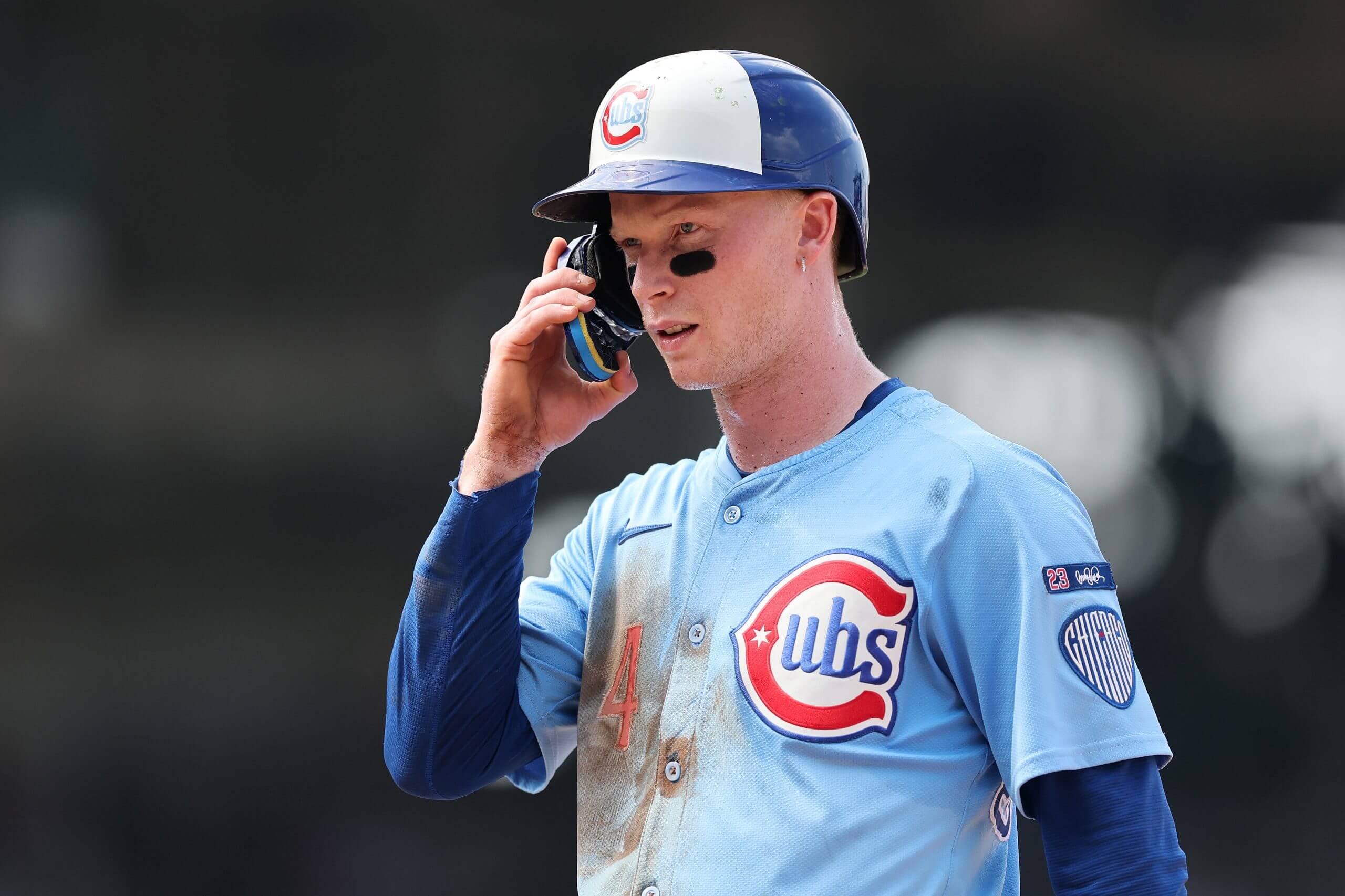 Pete Crow-Armstrong, in a light blue jersey over a dark-blue long-sleeved shirt, pulls on the protective flap of his batting helmet.