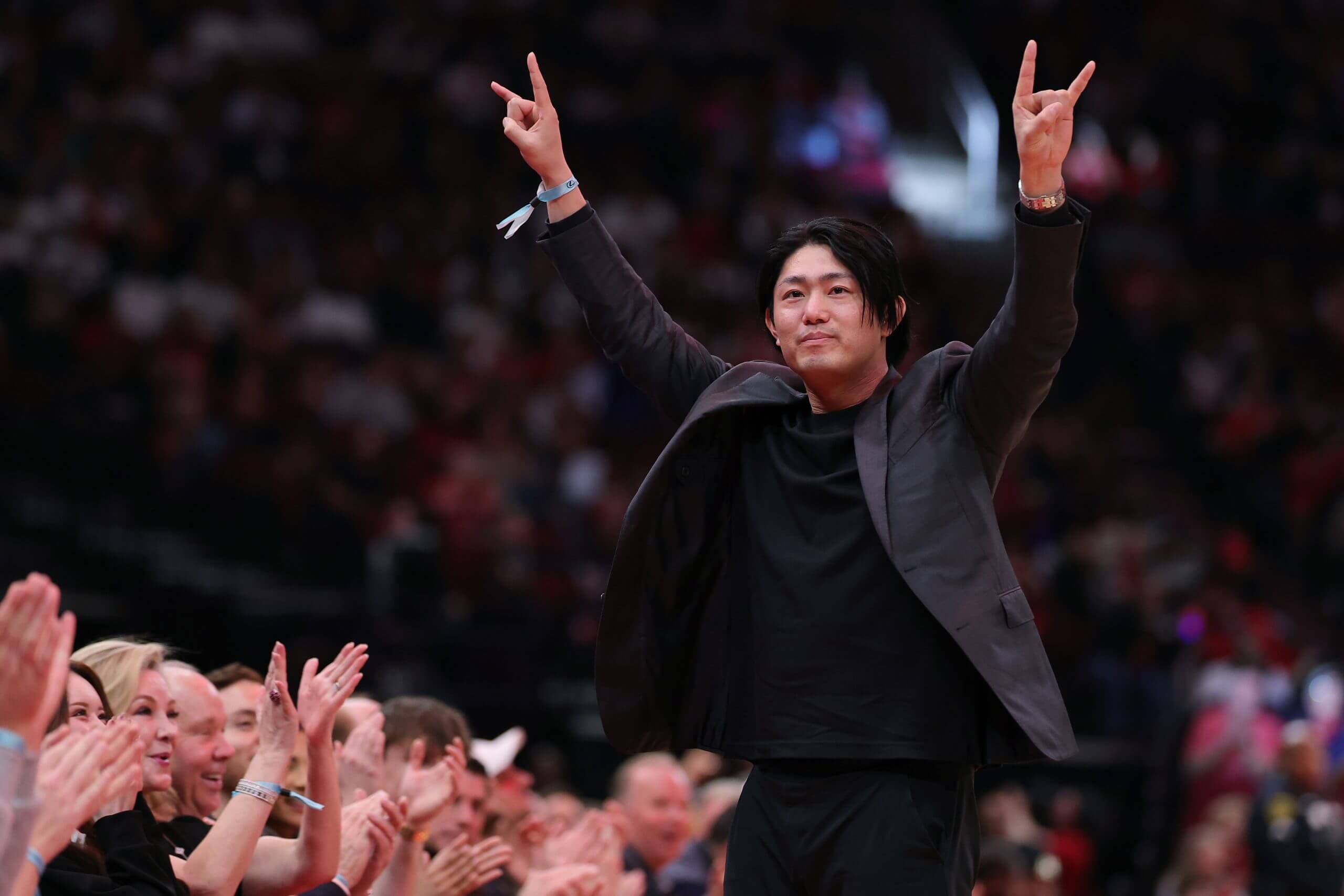 Tatsuya Imai throws his arms up in front of a cheering crowd.