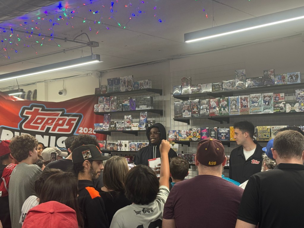 Lawrence Butler speaking to fans with rows of cards and promotional branding behind him.
