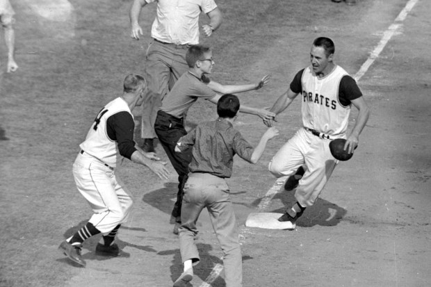 Jubilant Pittsburgh Pirates fans rush onto the field to congratulate second baseman Bill Mazeroski as he rounds third base after hitting a ninth-inning home run to win Game 7 of baseball's World Series against the New York Yankees in Pittsburgh, Pa., on Oct. 13, 1960. (AP Photo/Harry Harris, File)