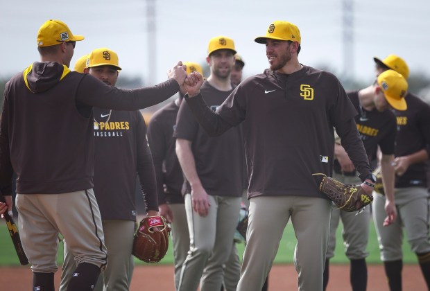 Joe Musgrove, center, high fives special assistant Craig Stammen during Padres spring training workouts at the Peoria Sports Complex on Feb. 13, 2025 in Peoria, Ariz.. (Meg McLaughlin / The San Diego Union-Tribune)