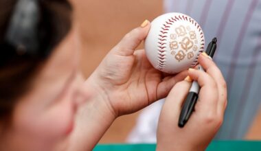 A fan holds a baseball with pretzels printed on it while waiting for autographs.
