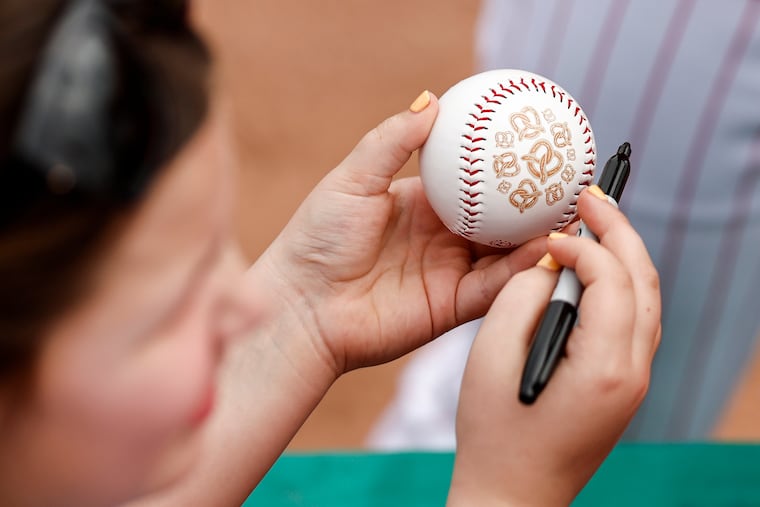 A fan holds a baseball with pretzels printed on it while waiting for autographs.