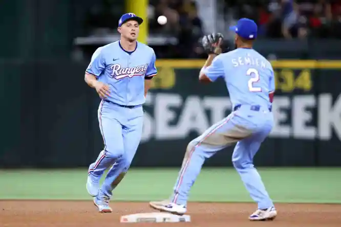 Jul 27, 2025; Arlington, Texas, USA; Texas Rangers shortstop Corey Seager (5) tosses the ball to second baseman Marcus Semien (2) to turn a double play during the game against the Atlanta Braves at Globe Life Field. Mandatory Credit: Tim Heitman-Imagn Images