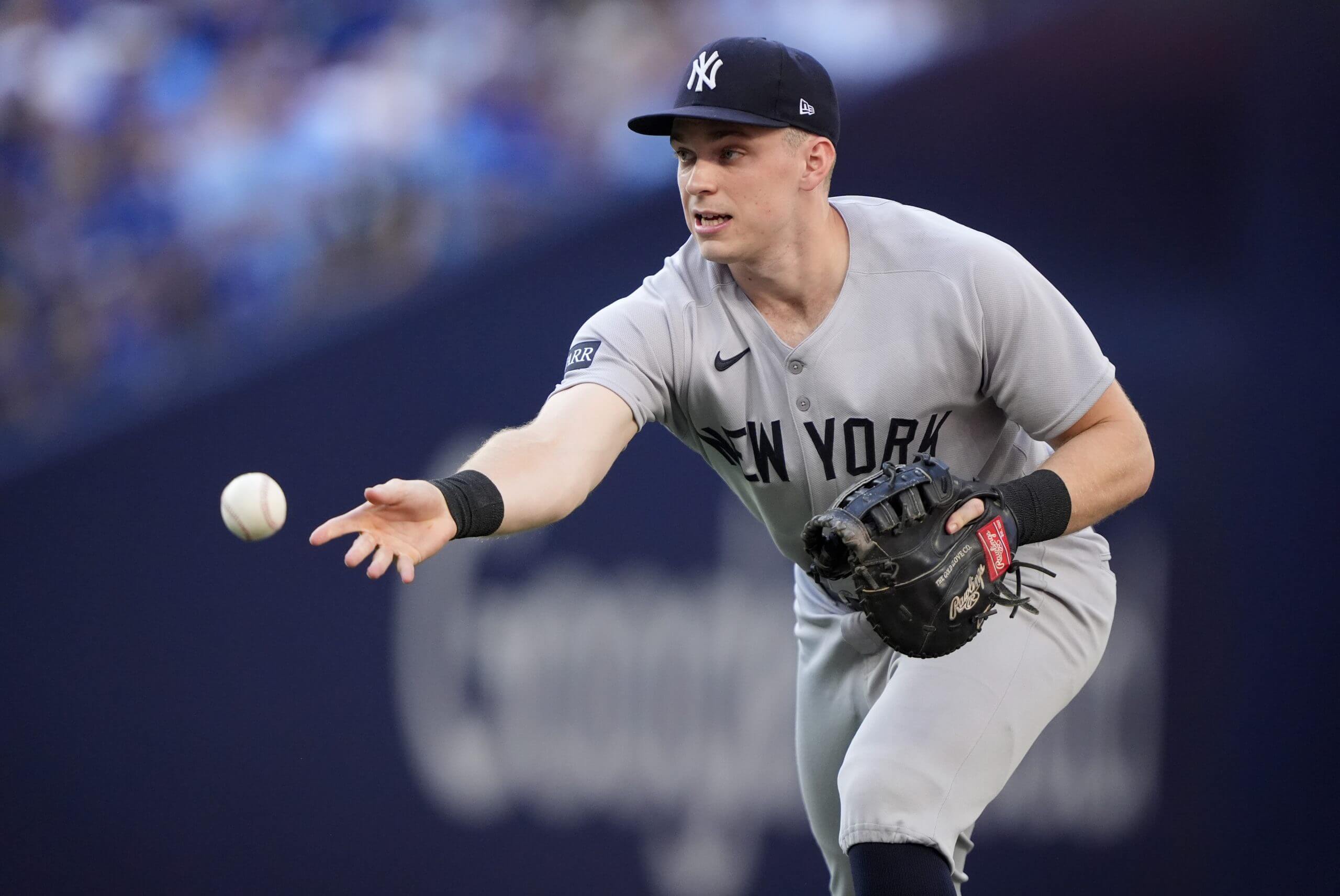 Ben Rice, facing left, tosses the ball to first base with his right hand.