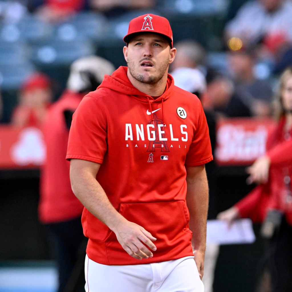 Mike Trout of the Angels in a red hoodie and cap, on the field.