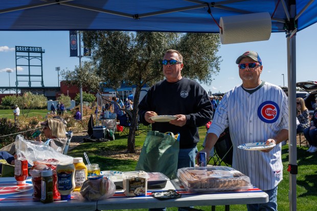 From left, Tom Pierce and Brian Boys, both from Chicago, wait for players to pass while walking to the stadium before the Cubs play the against the Chicago White Sox during the Cubs and White Sox first spring training game of the year at Sloan Park Friday Feb. 20, 2026 in Mesa, Ariz. (Armando L. Sanchez/Chicago Tribune)