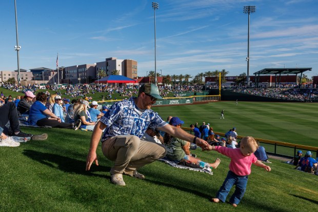 George Obrochta and his 1-year-old daughter Emilia Obrochta, from Chicago, walk behind outfield as the Chicago Cubs play against the Chicago White Sox in the ninth inning during the Cubs and White Sox first spring training game of the year at Sloan Park Friday Feb. 20, 2026 in Mesa, Ariz. (Armando L. Sanchez/Chicago Tribune)