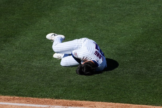 Chicago Cubs first baseman Jonathon Long (91) lays on the ground after he was hit by Texas Rangers left fielder Mark Canha (33) while he ran to first base after hitting a single during the fourth inning of a Cactus League game at Sloan Park Saturday Feb. 21, 2026 in Mesa, Ariz. (Armando L. Sanchez/Chicago Tribune)