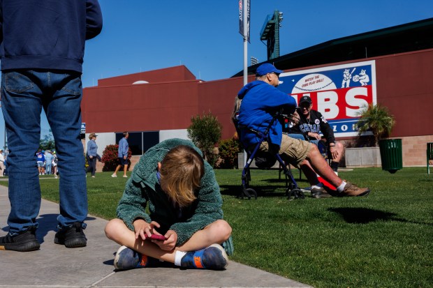 8-year-old Briggs looks at a phone while waiting in line before the Chicago Cubs play the Texas Rangers in a Cactus League game at Sloan Park Saturday Feb. 21, 2026 in Mesa, Ariz. (Armando L. Sanchez/Chicago Tribune)