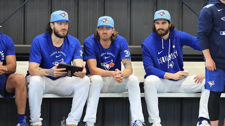 Blue Jays pitchers sit and watch practice in blue Blue Jays gear