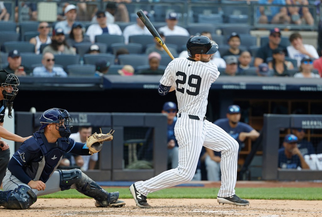 New York Yankees batter Austin Slater hitting a ground ball as the Tampa Bay Rays catcher prepares to field.