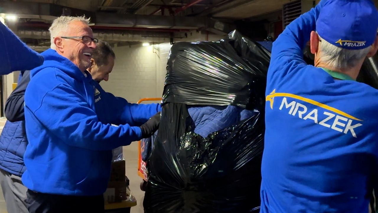 Amelung and another mover wrap a X-ray machine with padding before loading it onto a truck.