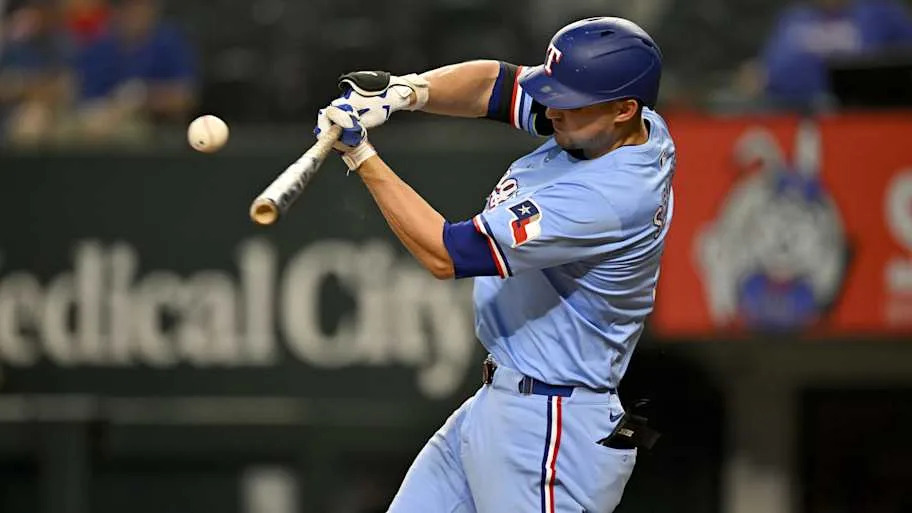 Texas Rangers shortstop Corey Seager hits a baseball with a bat.