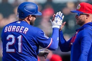 Texas Rangers designated hitter Jake Burger gets a hand from manager Skip Schumaker after...