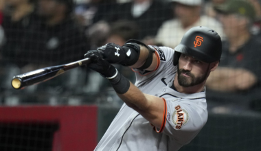 A baseball player wearing a San Francisco Giants uniform swings a bat during a game, focusing intently on the ball.