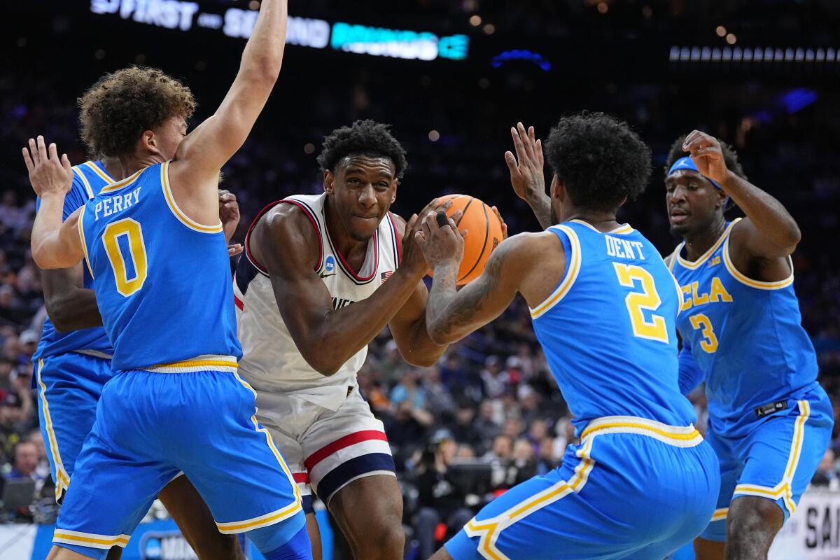 UConn's Tarris Reed Jr., center, tries to get through UCLA's Trent Perry, from left.