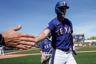 Texas Rangers outfielder Evan Carter celebrates on his way to the dugout after scoring on a...