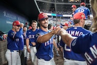 Texas Rangers pitcher Carter Baumler, center, gets a fist-bump in the dugout after he was...