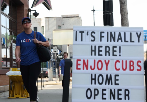 Meghan Flanigan, visiting from Las Vegas, walks past a welcome sign across from Wrigley Field, March 25, 2026, in Chicago. (John J. Kim/Chicago Tribune)