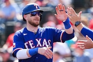 Texas Rangers catcher Danny Jansen gets a hand on his way to the dugout after hitting a...