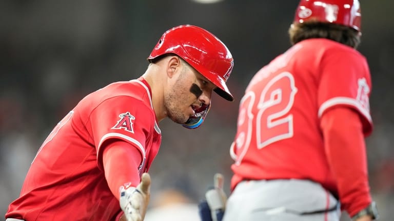 Los Angeles Angels' Mike Trout, left, celebrates with first base...