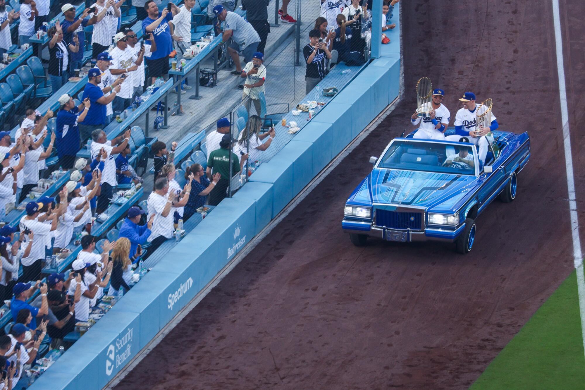 Miguel Rojas, left, and Freddie Freeman hold the Dodgers' 2024 and 2025 World Series trophies.