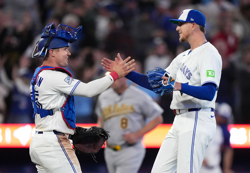 Toronto Blue Jays pitcher Jeff Hoffman (23) celebrates with teammate Toronto Blue Jays catcher Tyler Heineman, left, after defeating the Athletics during the ninth inning of an American League baseball game, in Toronto, Sunday, March 29, 2026. (Nathan Denette/The Canadian Press via AP)