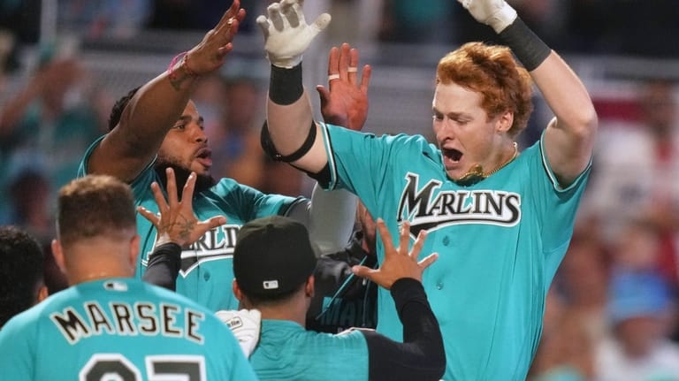 Miami Marlins' Owen Caissie, right, reacts after scoring on a...