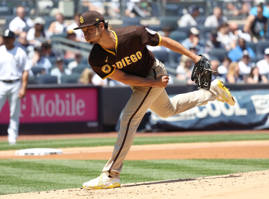 A baseball player pitching the ball with his body angled left.