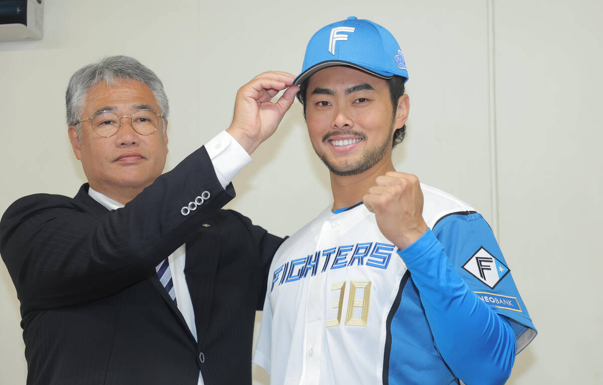 Taiwanese representative Lin Chia-Cheng, whose signing with Nippon-Ham has been confirmed, has his cap placed on his head by acting GM Masao Kida (left) (Photo by Shohei Uemura)