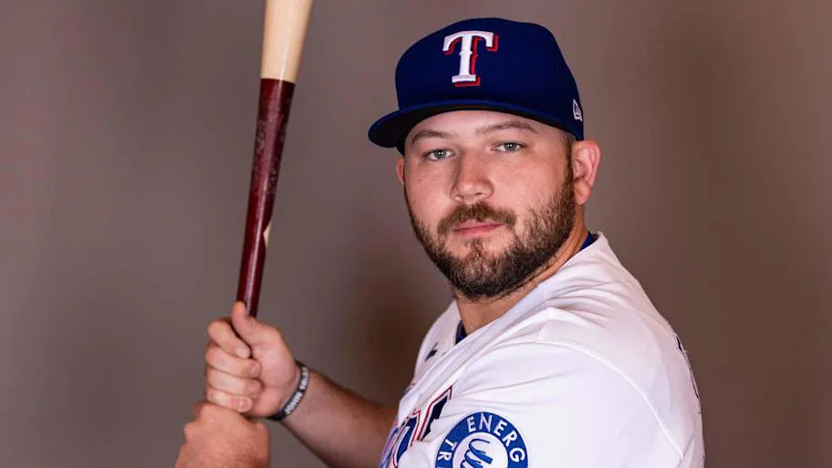 Texas Rangers infielder Jake Burger poses for a photo while holding a bat.