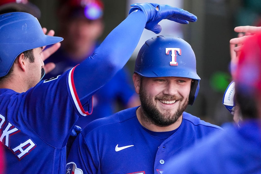 Texas Rangers first baseman Jake Burger gets a pat on the helmet from catcher Kyle...