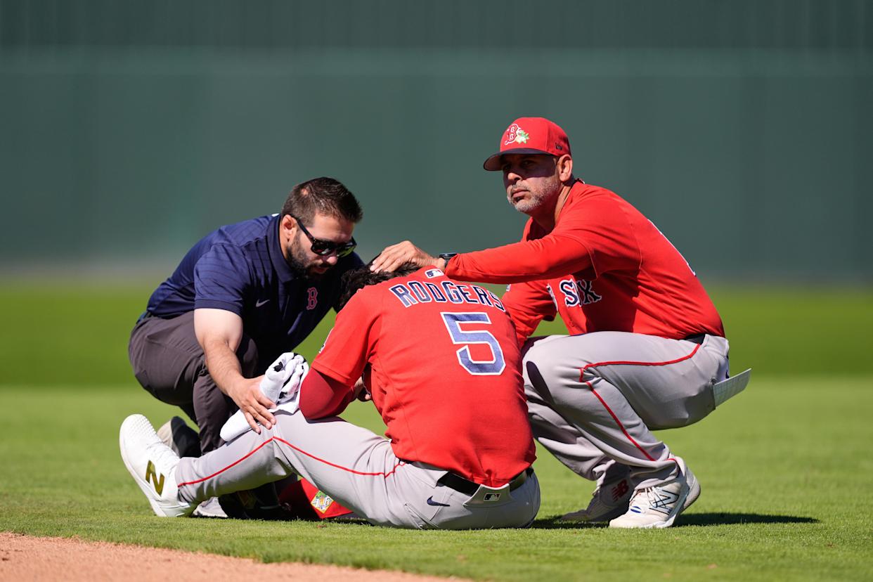 Boston Red Sox second baseman Brendan Rodgers (5) is tended to by a team trainer and manager Alex Cora (13) after being injured in the fourth inning of a spring training baseball game against the Minnesota Twins in Fort Myers, Fla., Wednesday, Feb. 25, 2026. (AP Photo/Gerald Herbert)