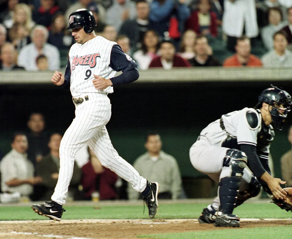 Gary Disarcina of the Anaheim Angels crosses the plate as catcher Jorge Posada of the New York Yankees awaits the throw.