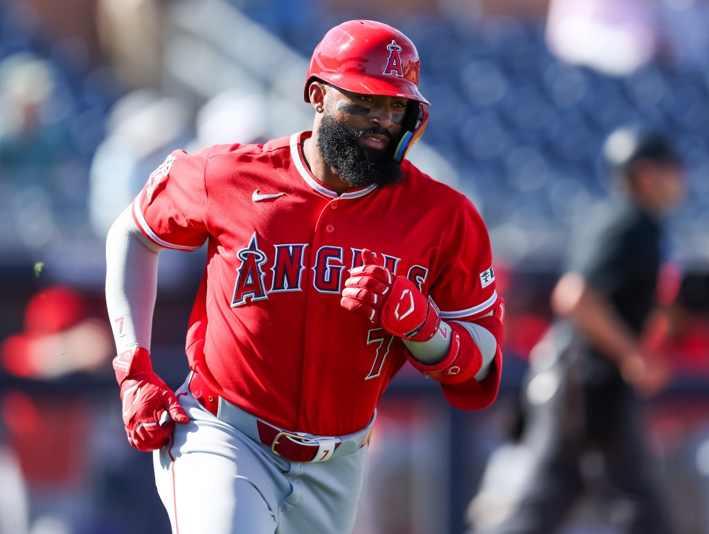 Jo Adell in a red Angels uniform and batting helmet rounding the bases.
