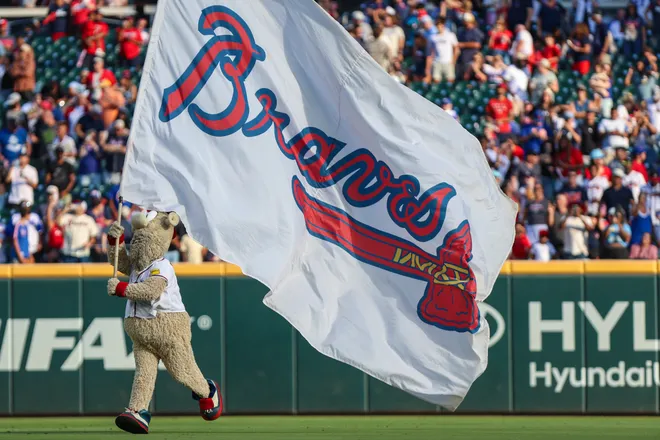 The Atlanta Braves mascot Blooper runs with the Atlanta Braves flag after a victory against the Pittsburgh Pirates at Truist Park.