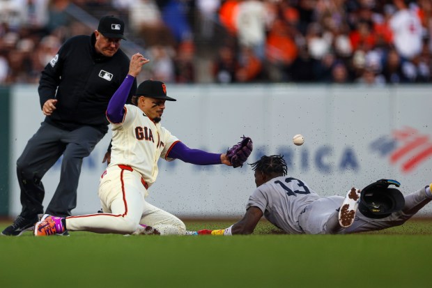 The ball gets by San Francisco Giants' Willy Adames (2) as New York Yankees' Jazz Chisholm Jr. (13) slides into second for a steal in the fifth inning during Opening Night at Oracle Park in San Francisco, Calif., on Wednesday, March 25, 2026.  (Shae Hammond/Bay Area News Group)