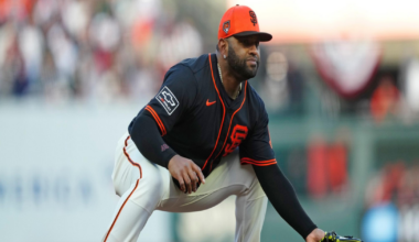 A baseball player in a black and orange San Francisco Giants uniform crouches in a ready fielding position on the infield dirt.