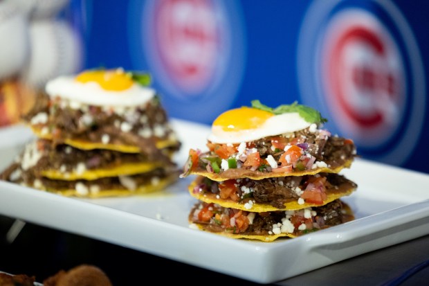 The Tostada Stack on display during the Taste of Wrigley Field event in the Home Plate Room on March 20, 2026. The dish includes tostadas layered with chili beef, refried beans, queso fresco, Pico de Gallo, cream, fried egg and salsa. (Josh Boland/Chicago Tribune)