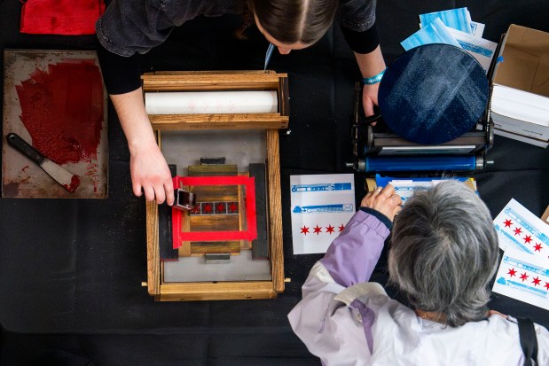 A vendor helps an attendee prep the letter press by Starshaped Press at the Chicago Stationery Fest in Ravenswood on March 15, 2026. (Nate Swanson/for the Chicago Tribune)