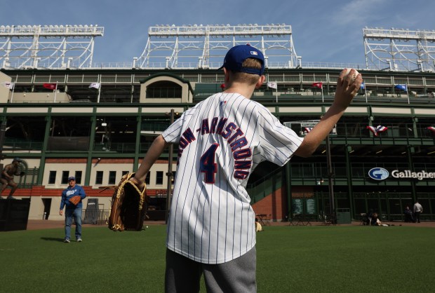 Cubs fan Cameron Swank, 10, wears his Pete Crow-Armstrong jersey as he plays catch with his grandfather at Gallagher Way outside Wrigley Field, March 25, 2026, ahead of opening day in Chicago. (John J. Kim/Chicago Tribune)