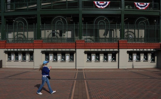 A Cubs fan looks up at home opener banners while walking past Wrigley Field, March 25, 2026, in Chicago. Opening day is Thursday between the Cubs and Nationals. (John J. Kim/Chicago Tribune)