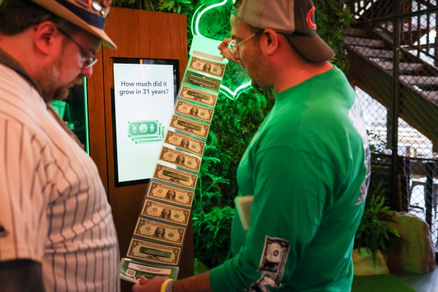 Kevin Urbanski, right, shows Matthew Hallberg the $11 he got out of the fintech company Acorns compounding vending machine at Big Star Wrigleyville on opening day, March 26, 2026. (Eileen T. Meslar/Chicago Tribune)