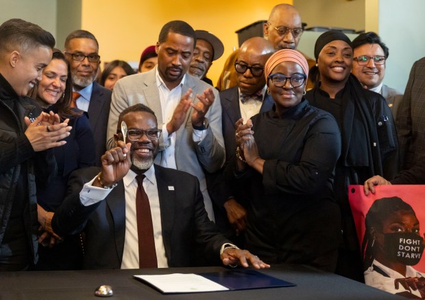 Mayor Brandon Johnson signs a veto of an ordinance pausing a phaseout of the subminimum tipped wage as he's joined by supporters, on March 25, 2026, at Let's Eat to Live restaurant in Chicago's Woodlawn neighborhood. (Brian Cassella/Chicago Tribune)