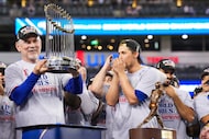 Texas Rangers manager Bruce Bochy holds the Commissioner’s Trophy to the cheers of shortstop...