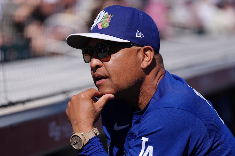 Photo of a man in a blue shirt with his hand on his chin.