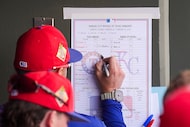 Texas Rangers bench coach Luis Urueta makes changes to the lineup card during the third...
